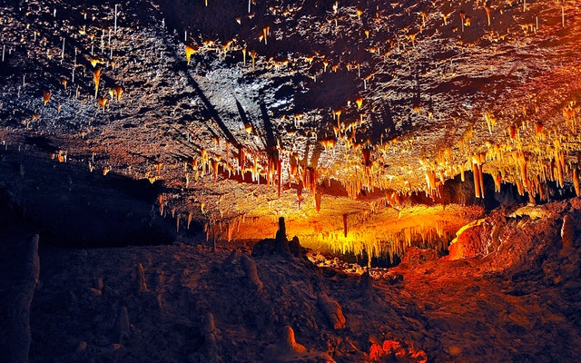 Jaskyňa nasvietená na červeno a oranžovo s kvapľami